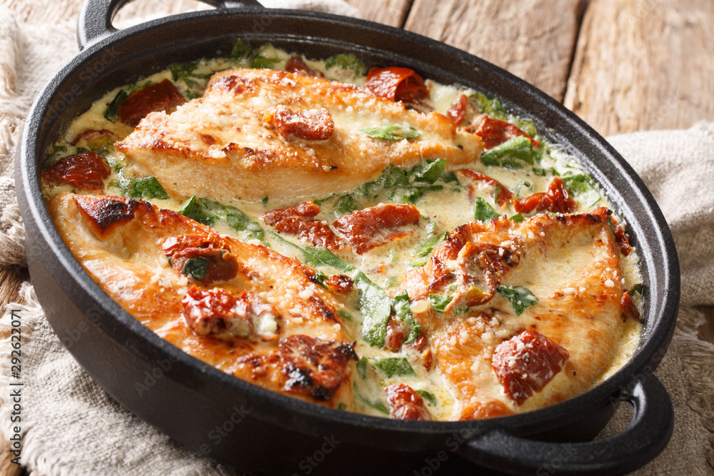 Gourmet chicken with sun-dried tomatoes and spinach in cheese sauce close-up in a pan on the table. horizontal