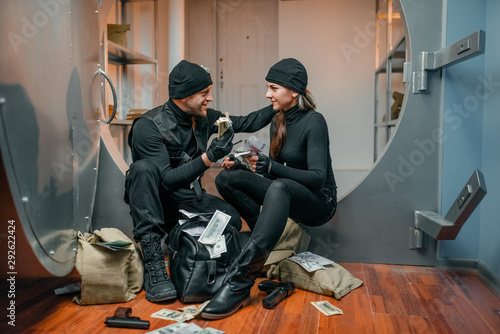 Canvas Print Two robbers in black uniform stuff bags with money