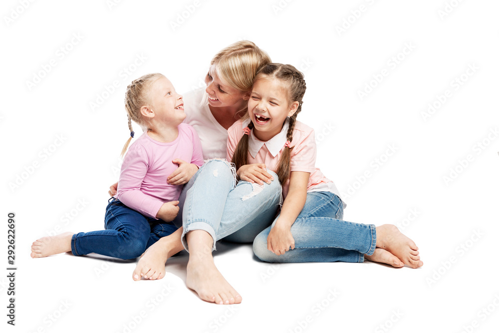 Mom and daughters are sitting and laughing. Love and tenderness. Isolated over white background. Mom and daughters are sitting and laughing. Love and tenderness. Isolated over white background.