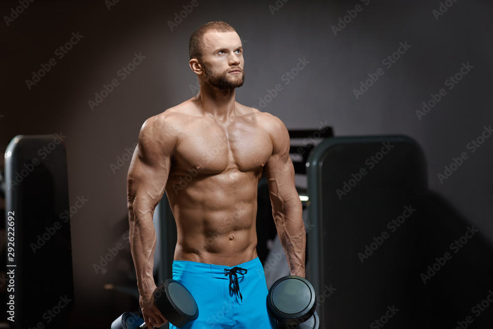 Muscular fit male athlete training and lifting dumbbells