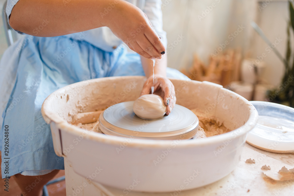 Female potter hands works on pottery wheel