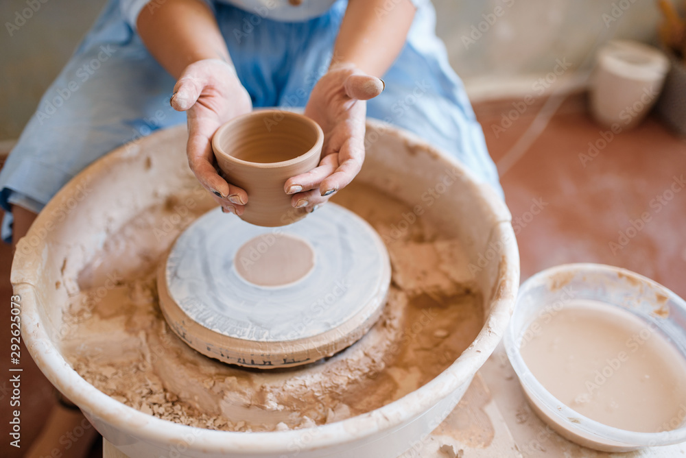 Female master holds wet pot over the pottery wheel Female master holds wet pot over the pottery wheel