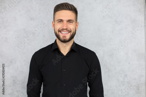 Happy brunette man is smiling at camera isolated over gray background