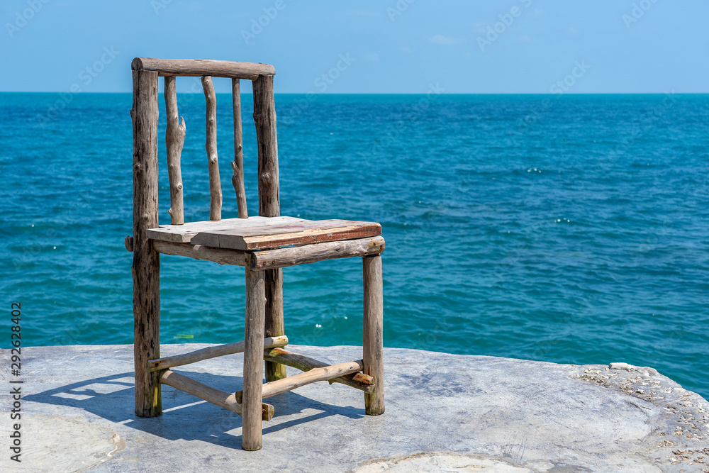 Wooden chair in empty cafe next to sea water in tropical beach . Island Koh Phangan, Thailand Wooden chair in empty cafe next to sea water in tropical beach . Island Koh Phangan, Thailand