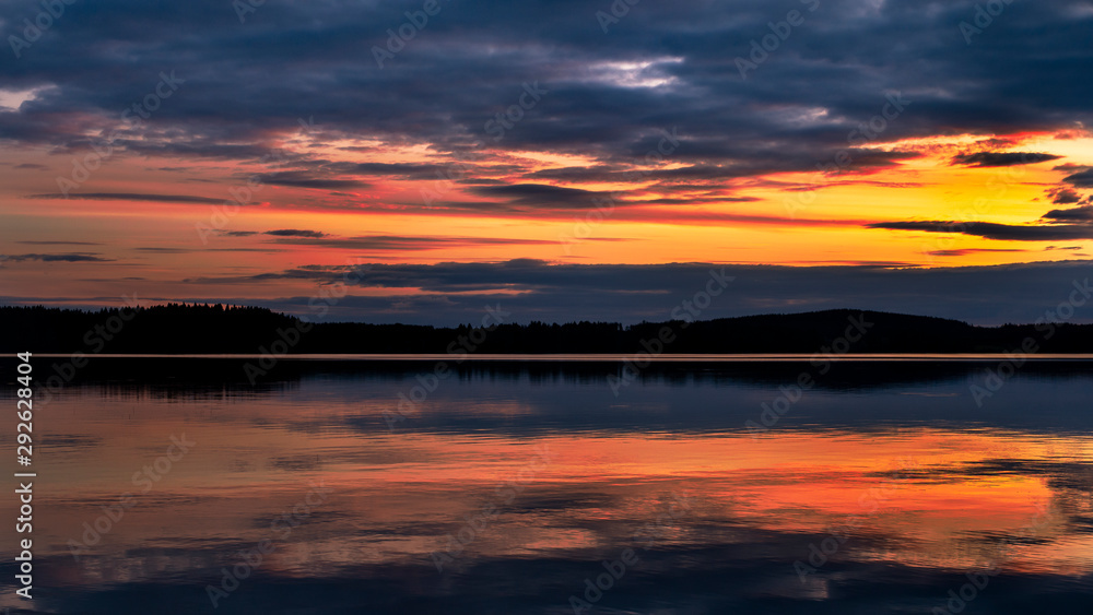 Water reflections at midnight sun at serene lake in finlandd Water reflections at midnight sun at serene lake in finlandd