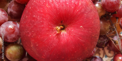 red apple with grapes. on top of the macro. background