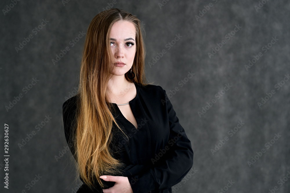 Portrait of a pretty brunette girl with beautiful hair, excellent make-up, beautiful face skin in a black blouse on a dark background. Made in the studio. Portrait of a pretty brunette girl with beautiful hair, excellent make-up, beautiful face skin in a black blouse on a dark background. Made in the studio.