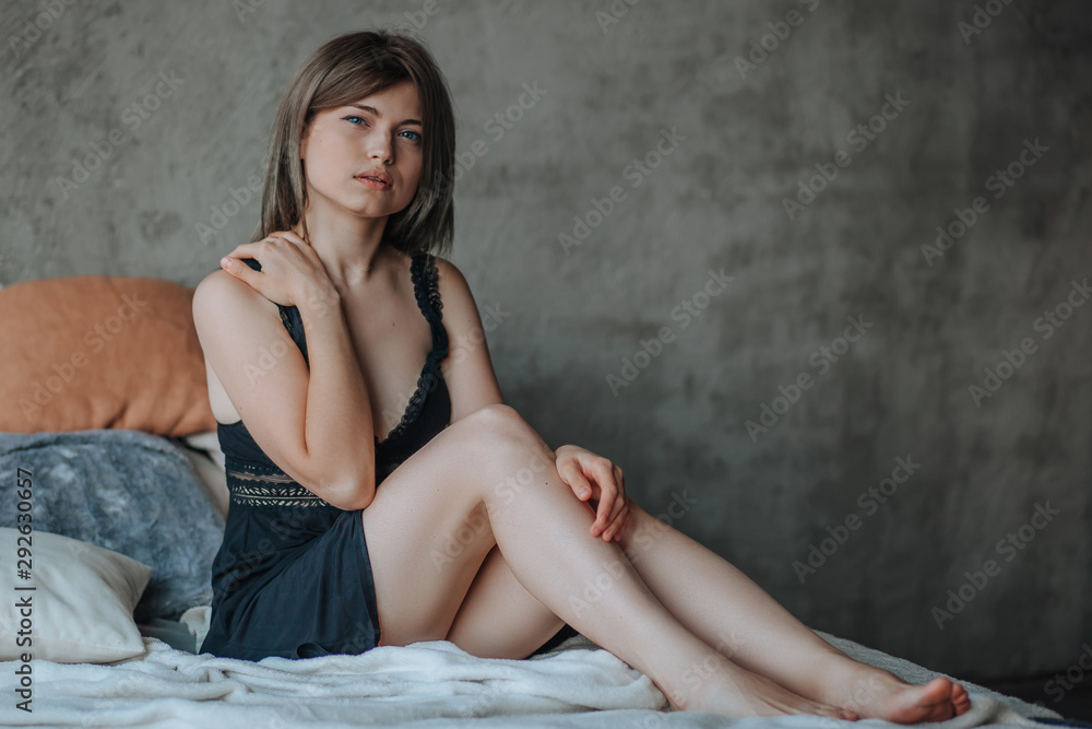 Naklejka premium Cute girl sitting on bed in morning in black lingerie