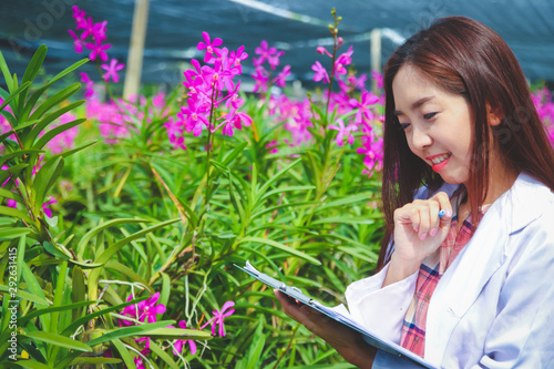 The girl wore a white researcher uniform. Stand to record information on paper In the orchid garden