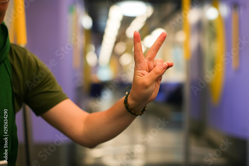 Close up female hand in empty subway car. Two fingers sign victory of woman's hand in selective focus.