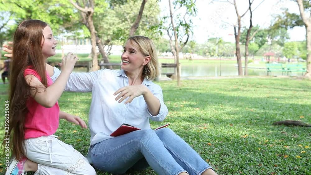 Mother and daughter reading a book in the park . mom huging and kissing girl . family . grandparent and grandchild or grandmother and granddaughter . kid playful surprise , child Mother and daughter reading a book in the park . mom huging and kissing girl . family . grandparent and grandchild or grandmother and granddaughter . kid playful surprise , child