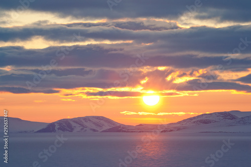 Midnight sun in spring in the Arctic. At the end of May, on the coast of the Arctic Ocean, the sun does not go beyond the horizon all night. East Siberian Sea, Chukotka, Russia. Polar region.
