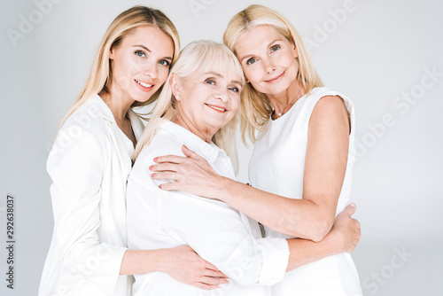 three generation blonde women embracing isolated on grey