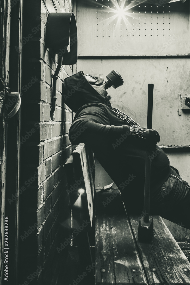 Fototapeta premium Man with gas mask and a hammer in machine room. Nuclear, Biological and Chemical danger concept.
