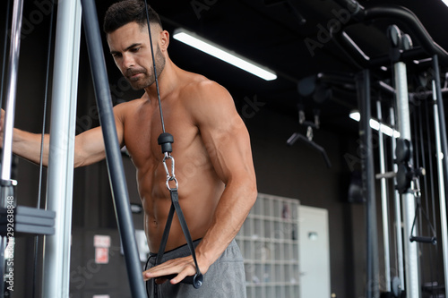 Fit and muscular man trains pectoral muscles on a block simulator in the gym.