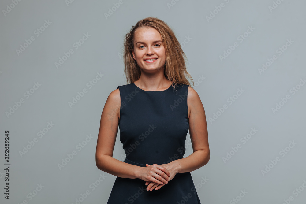 Beautiful smiling girl wearing blue dress and folded arms chest on grey background Beautiful smiling girl wearing blue dress and folded arms chest on grey background