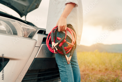 Close up Woman connecting battery cable copper wire for jumper repair and maintenance electric of engine car problem, broken her self service transportation, Vehicle stop engine between travel photo