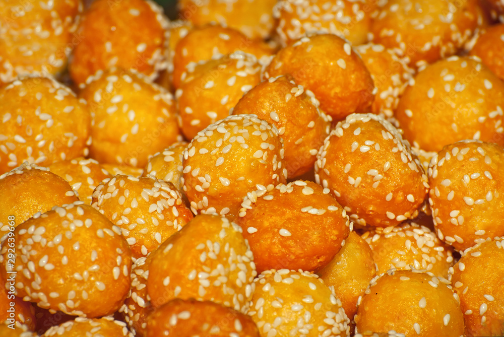 Lots of yellow cheese balls. Balls of sesame seeds close up. Homemade food at a city street festival.