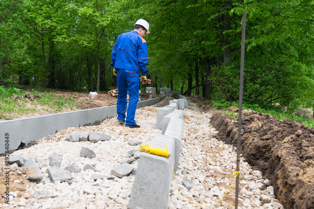 worker on the construction of a new pedestrian road in a city park worker on the construction of a new pedestrian road in a city park