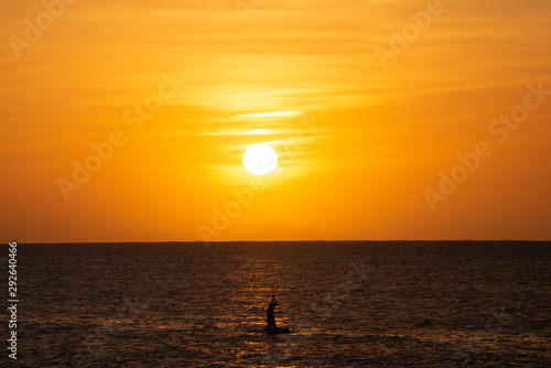 Beautiful sunset over Mediterranean sea with silhouette of solitary paddleboarder