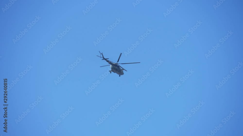 Military green and white chopper hovering and flying slowly in the blue air in autumn Military green and white chopper hovering and flying slowly in the blue air in autumn