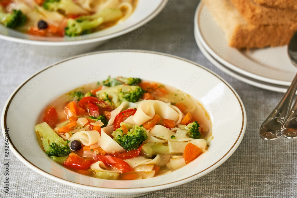 Soup with fresh vegetables and noodles in a white bowl Soup with fresh vegetables and noodles in a white bowl