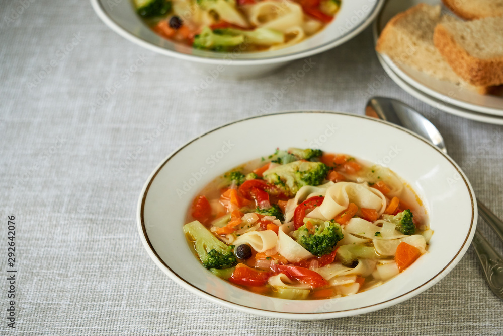 Soup with fresh vegetables and noodles in a white bowl 