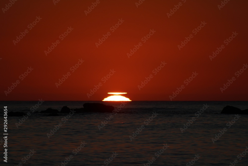 sun reaching the horizon in the sea on a red sky sunset sun reaching the horizon in the sea on a red sky sunset