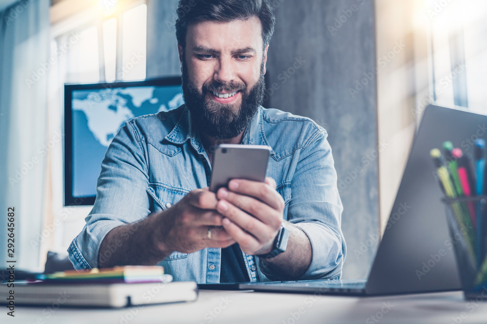 Man sitting at desk and holding mobile phone in hand. Office worker taking  selfie on his