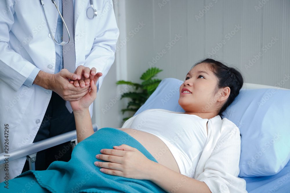 Obraz premium A male doctor shakes hands with a pregnant woman near birth to ensure that it is safe from birth. Health concept
