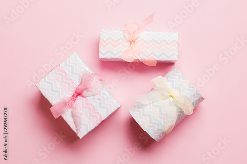 wrapped Christmas or other holiday handmade present in paper with Colored ribbon on pink background. Present box, decoration of gift on colored table, top view © sosiukin