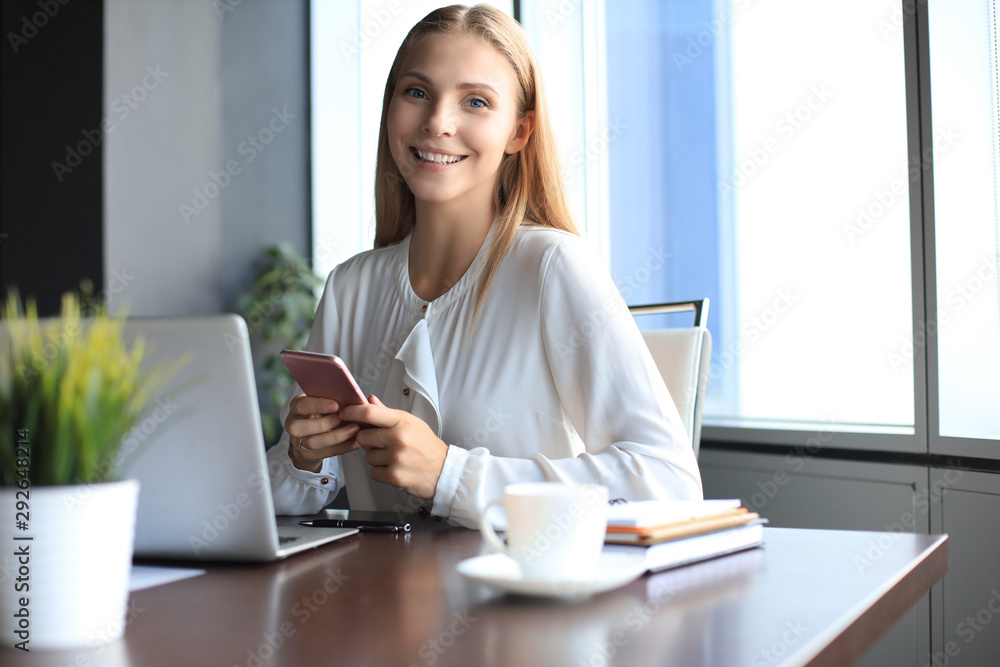 Beautiful smiling business woman is sitting in the office and looking at camera Beautiful smiling business woman is sitting in the office and looking at camera