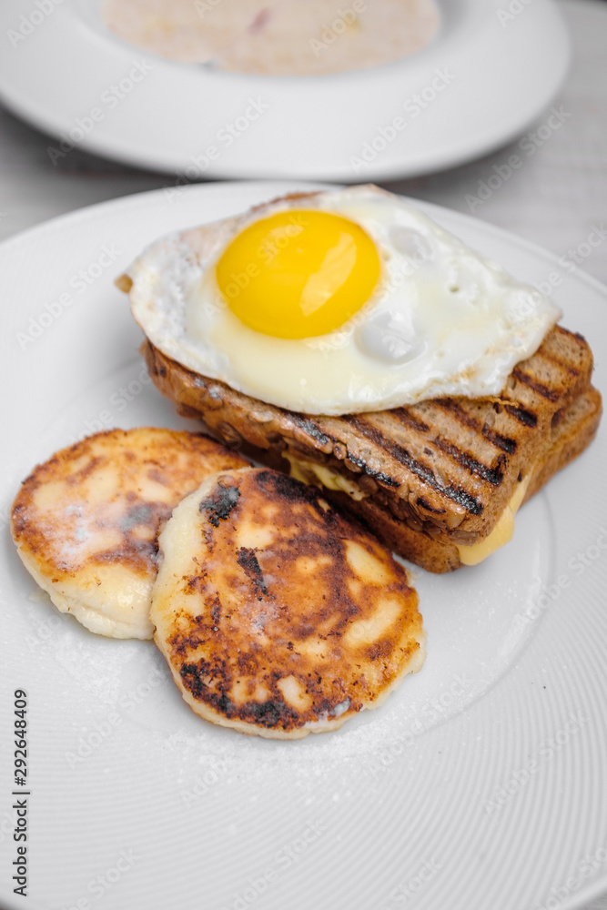 Photo Breakfast of fried eggs, cheese pancakes, toast , on a light white background in natural light 