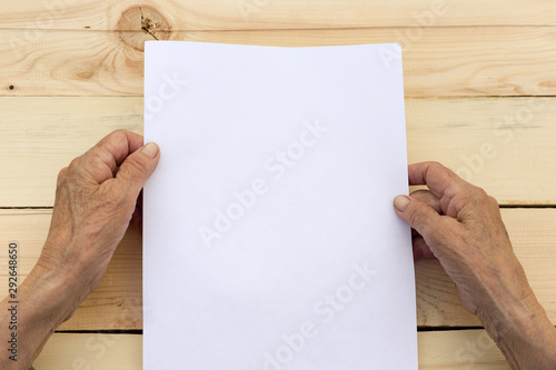 Old hands hold a blank sheet of paper. The concept of new beginnings, active old age, testament.