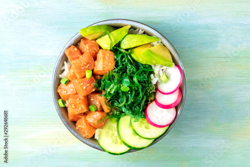 Salmon poke with avocado, wakame and cucumber, shot from above on a teal blue ba Fototapet