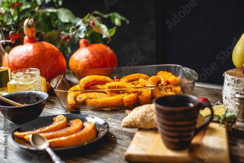Slices of baked orange pumpkin with honey and cinnamon on a wooden table. Autumn dish as a dessert