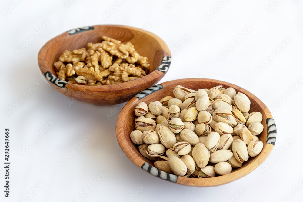 Chestnuts and pistachios in wooden bol as appertiser with drinks against a white background Chestnuts and pistachios in wooden bol as appertiser with drinks against a white background