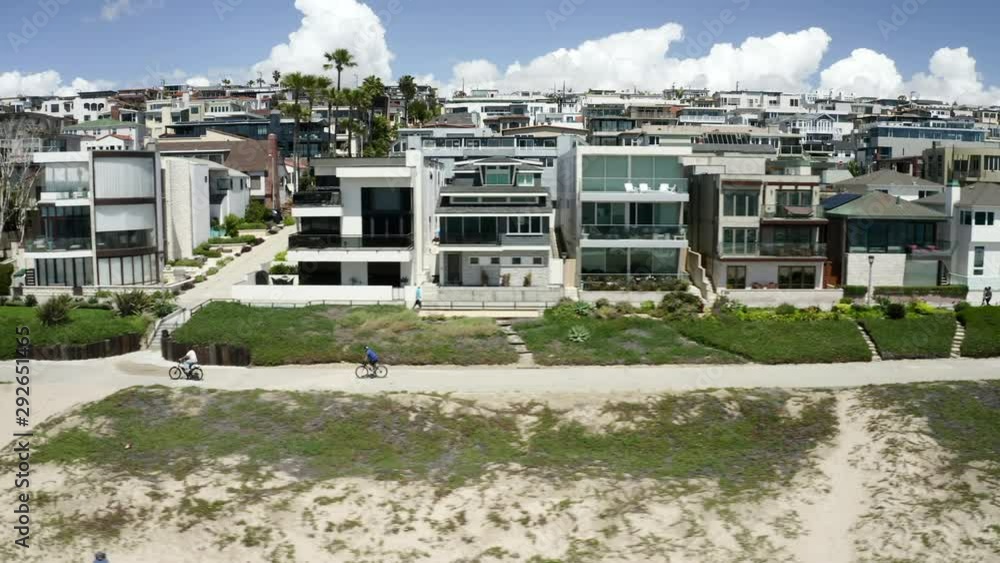 Aerial: People Riding Bikes on a Beach Path in Front of Houses - Manhattan Beach, California Aerial: People Riding Bikes on a Beach Path in Front of Houses - Manhattan Beach, California