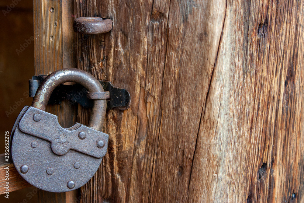 Rusty padlock on a door close-up. An old castle hangs on a wooden door. Rusty padlock on a door close-up. An old castle hangs on a wooden door.