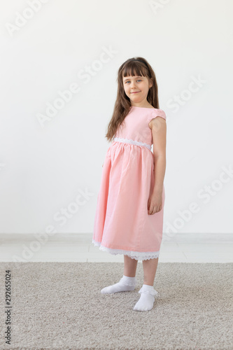 Little girl is a model, in a pink dress in studio