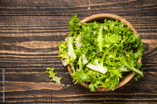 Photos Green salad frieze on dark wooden table.