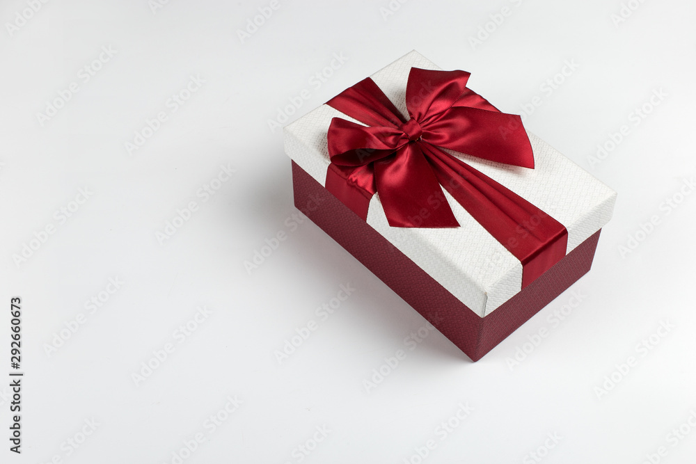 Gift with a red ribbon and a bow on a white background, copy space. Gift with a red ribbon and a bow on a white background, copy space.