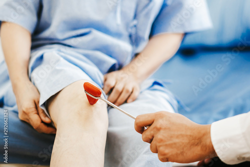 Doctor checking reflexes of a patient with reflex hammer photo