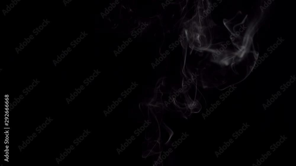 White filament smoke from incense sticks swirls in the dark. Small cloud flows on a black background, place for text. White filament smoke from incense sticks swirls in the dark. Small cloud flows on a black background, place for text.