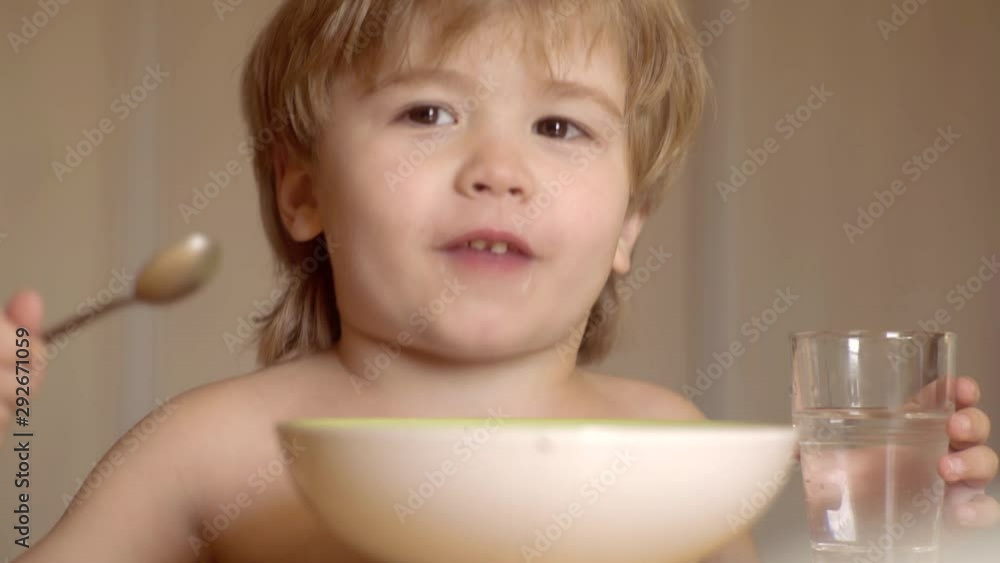 Happy baby boy spoon eats itself. Happy child have a breakfast. Happy child. Laughing cute child baby boy sitting in highchair and eating on kitchen background. Happy baby boy spoon eats itself. Happy child have a breakfast. Happy child. Laughing cute child baby boy sitting in highchair and eating on kitchen background.