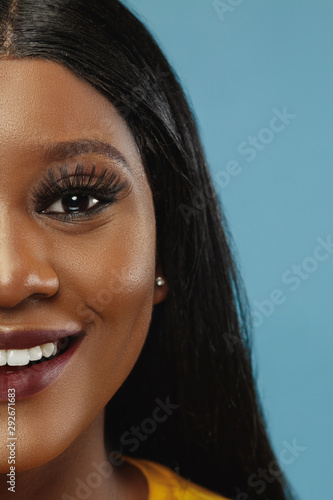 Fototapeta Naklejka Na Ścianę i Meble -  African-american young woman's close up portrait on studio background. Beautiful female model in white shirt with well-kept skin. Concept of human emotions, facial expression. Smiling, calm.
