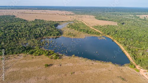 Aerial view of an Amazon lagoon surrounded partly by rests of original rainforest vegetation around, natural island in a agricultural area, environmental protection, Mato Grosso, Brazil