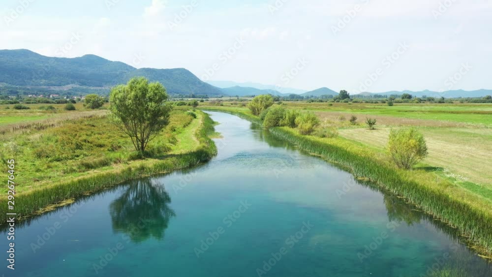 Beautiful Gacka river flowing between trees and fields, summer view, Lika region of Croatia, drone panning over the river surface Beautiful Gacka river flowing between trees and fields, summer view, Lika region of Croatia, drone panning over the river surface