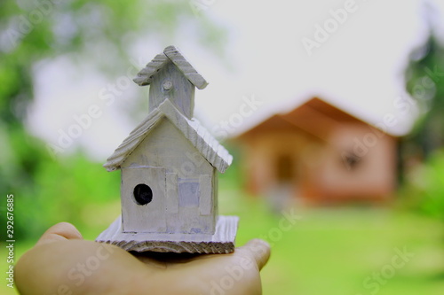 Hand holding wooden miniature house with background blur house,Home Future concept.  © Chaleow