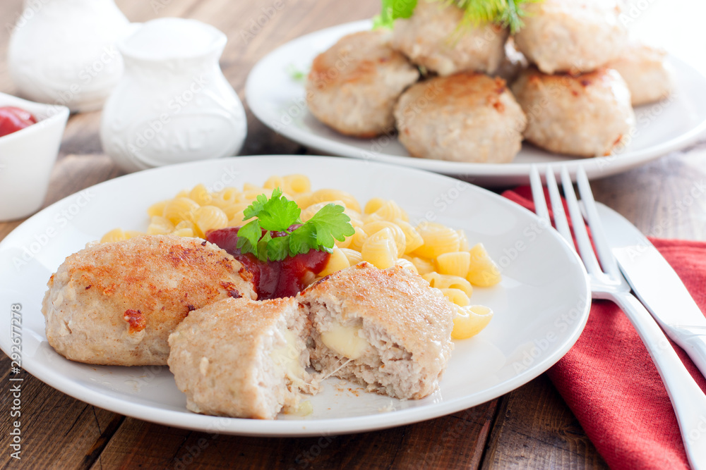 Homemade turkey cutlets with cheese filling on a white plate on a wooden table, horizontal